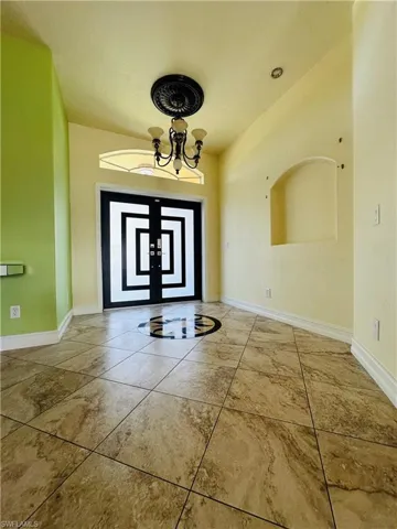 Tiled foyer entrance featuring a notable chandelier