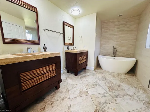 Bathroom with tile patterned floors, a bathtub, and vanity