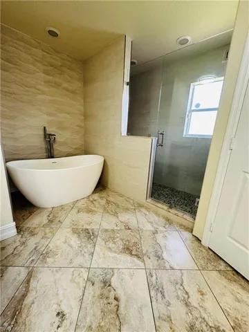 Bathroom with plus walk in shower, tile walls, a textured ceiling, and tile patterned floors