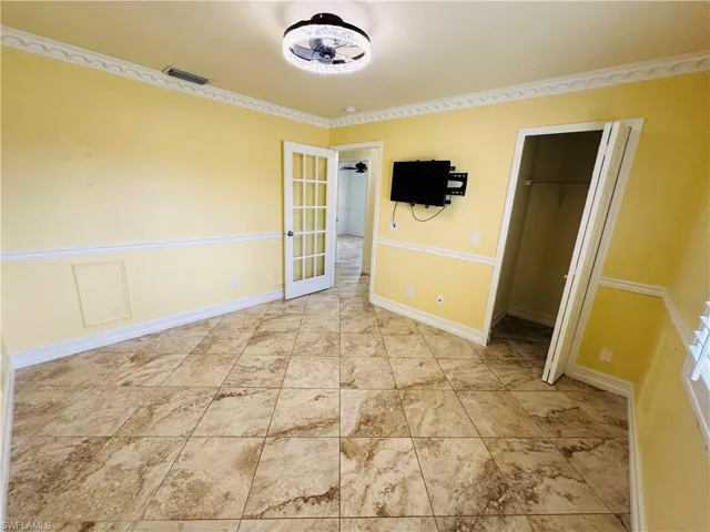 Unfurnished bedroom featuring a walk in closet, a closet, light tile patterned flooring, and french doors