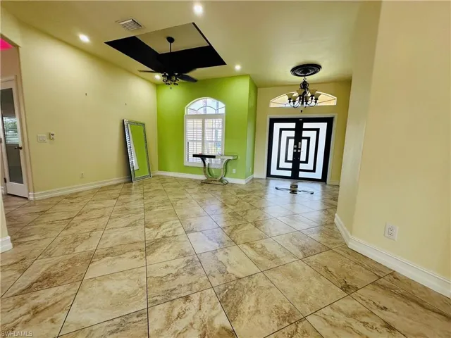 Tiled foyer with ceiling fan with notable chandelier
