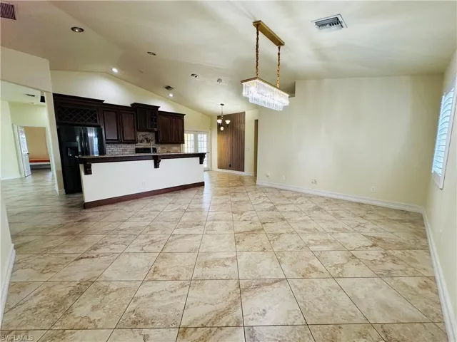 Kitchen with a notable chandelier, dark brown cabinets, light tile patterned floors, and tasteful backsplash