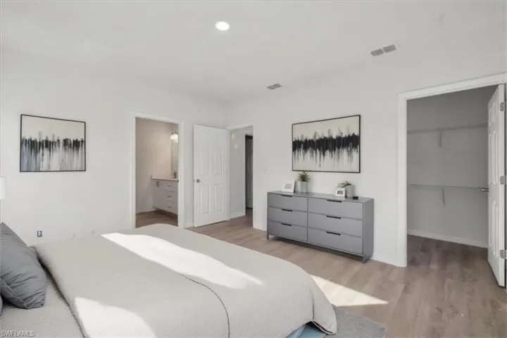 Bedroom with connected bathroom, a spacious closet, a closet, and light wood-type flooring
