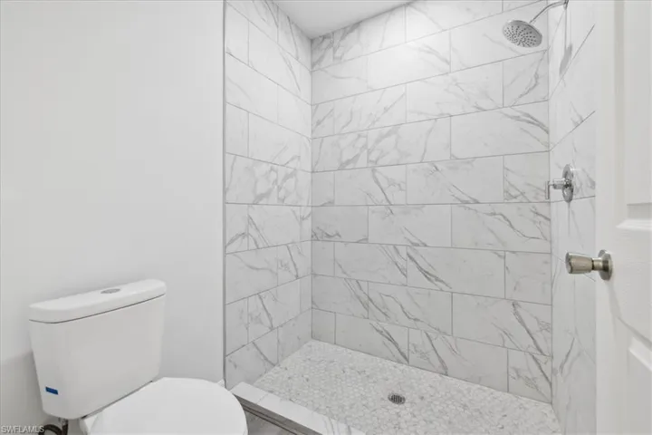 Bathroom featuring tiled shower and toilet