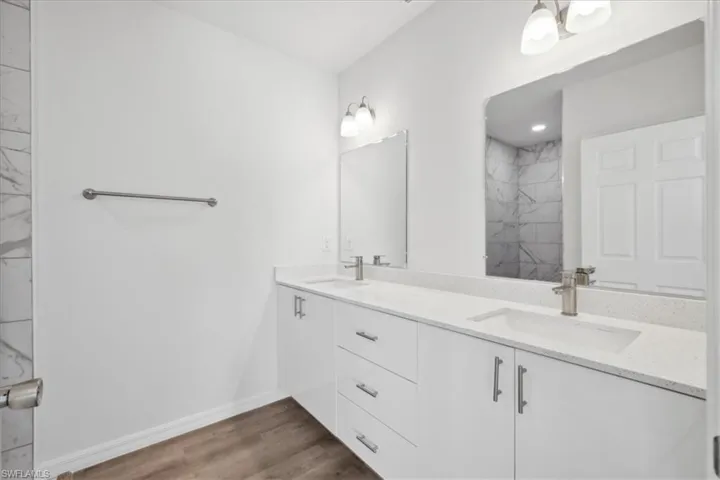 Bathroom featuring hardwood / wood-style floors, vanity, and tiled shower