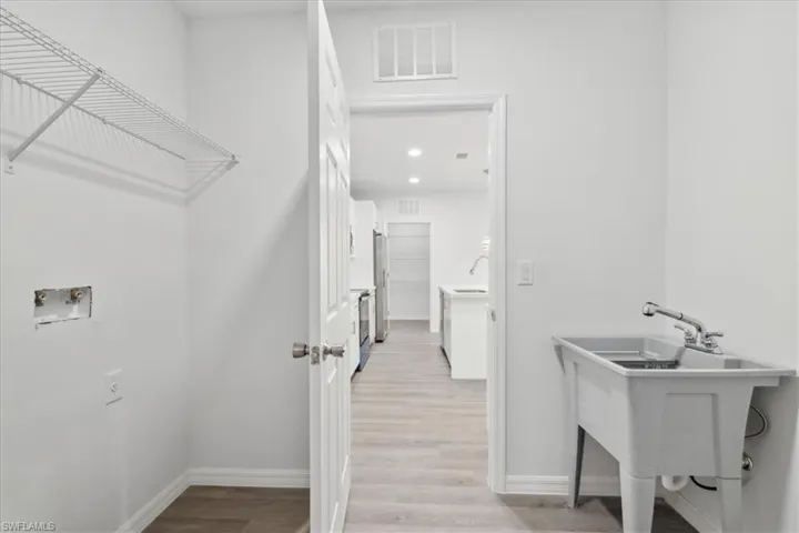 Clothes washing area with washer hookup, light hardwood / wood-style floors, and sink