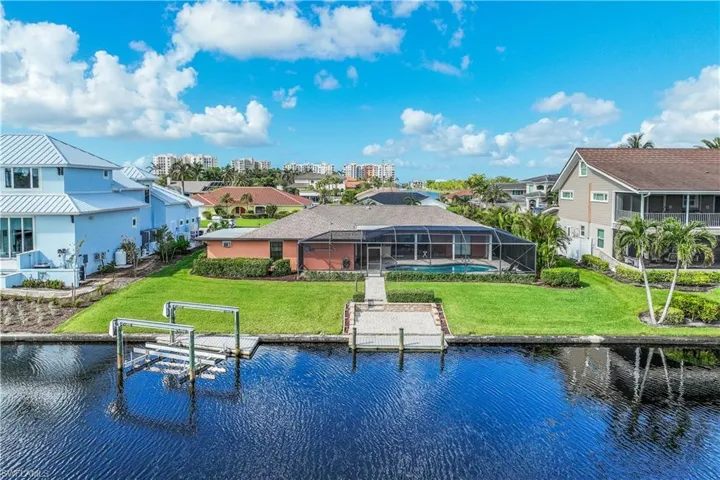 Back of property with a lawn, glass enclosure, and a water view