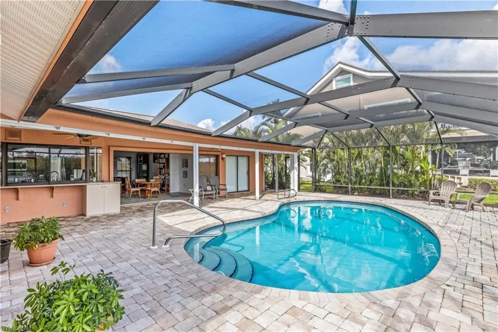 View of swimming pool with ceiling fan, a lanai, an outdoor bar, and a patio