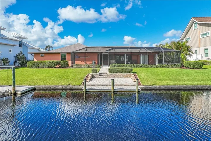 Dock area featuring a lanai, a lawn, and a water view