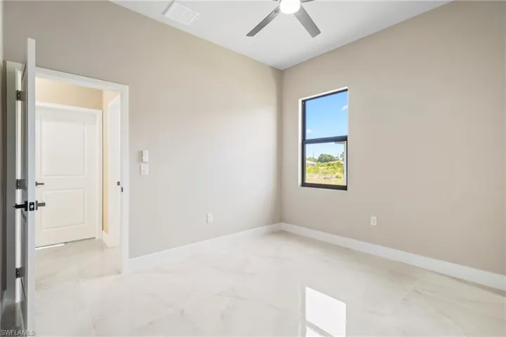 Unfurnished room featuring a ceiling fan and light marble finish flooring