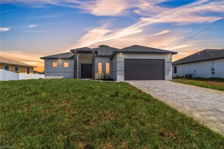 Prairie-style house with stucco siding, a garage, decorative driveway, and a shingled roof