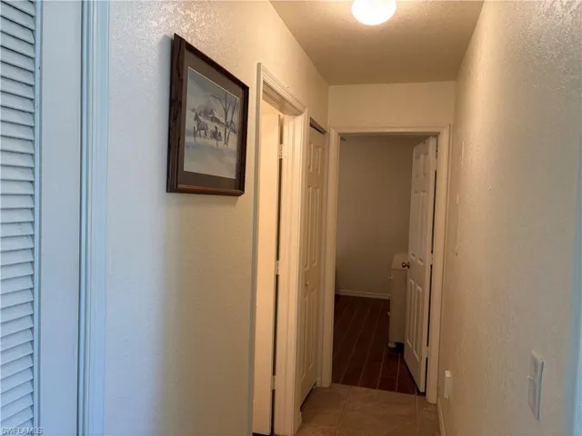 Hall featuring a textured wall and tile patterned flooring