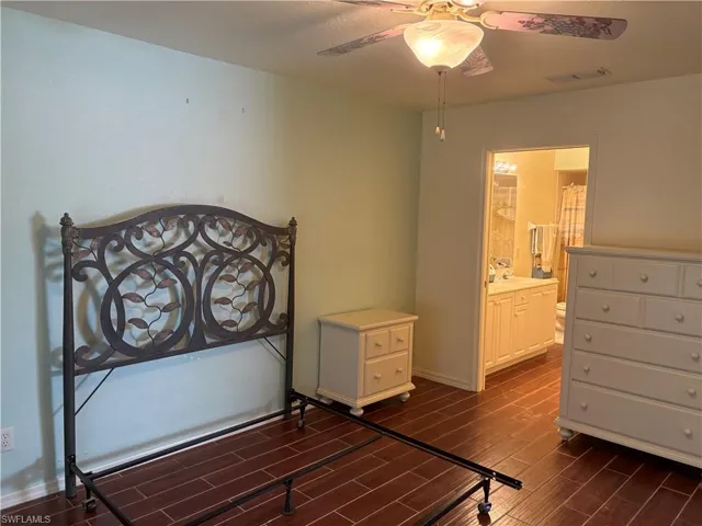 Bedroom with dark wood-style floors, ensuite bath, and ceiling fan