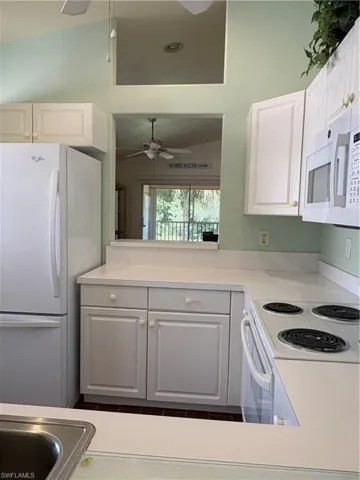 Kitchen with refrigerator, ceiling fan, white cabinetry, light countertops, and stove