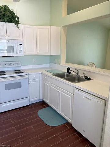 Kitchen featuring stove, dishwashing machine, dark wood-type flooring, a peninsula, and white cabinetry