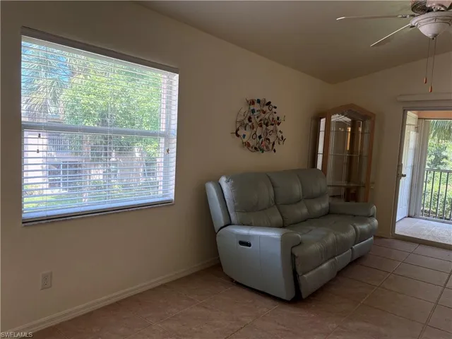 Living area featuring tile patterned flooring, a ceiling fan, and vaulted ceiling