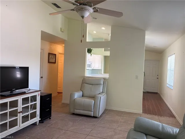 Tiled living room featuring lofted ceiling and a ceiling fan