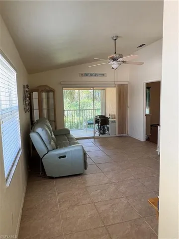 Living area featuring vaulted ceiling, ceiling fan, and light tile patterned floors