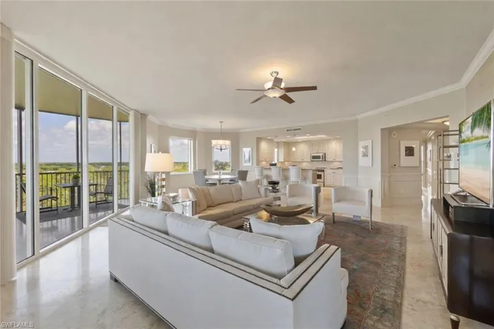 Living area featuring ornamental molding, expansive windows, a wainscoted wall, and a decorative wall