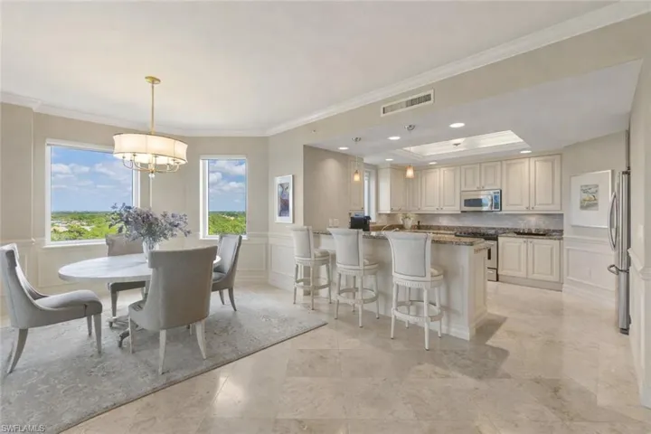Dining area featuring a decorative wall, ornamental molding, a wainscoted wall, and a tray ceiling
