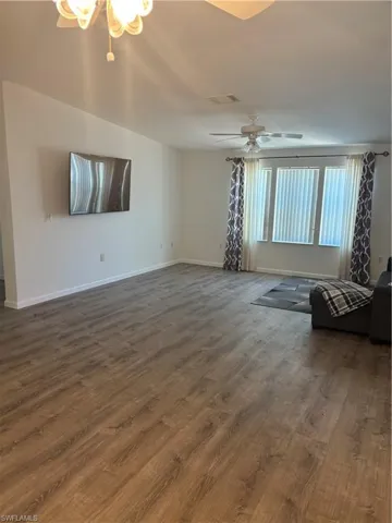 Unfurnished living room featuring dark hardwood / wood-style flooring and ceiling fan