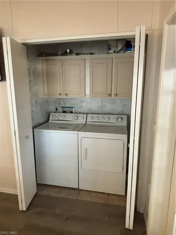 Laundry room with dark wood-type flooring, cabinets, washer hookup, and washing machine and clothes dryer