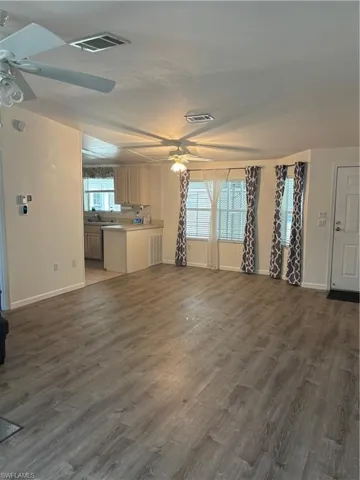 Unfurnished living room featuring sink, dark hardwood / wood-style flooring, and ceiling fan