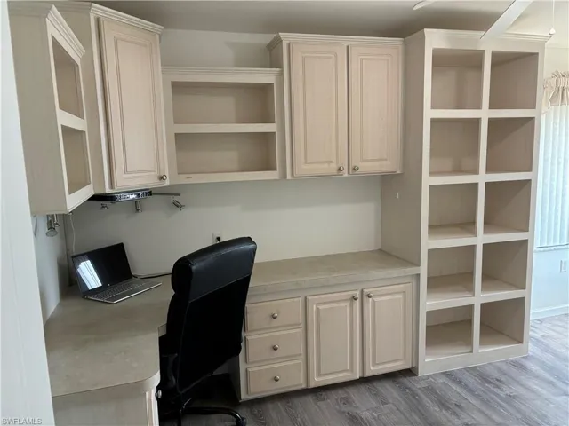 Unfurnished office with built in desk and wood-type flooring