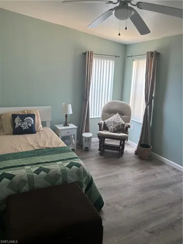 Bedroom with wood-type flooring, ceiling fan, and multiple windows