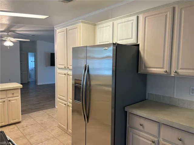 Kitchen with ornamental molding, light tile flooring, stainless steel refrigerator with ice dispenser, and ceiling fan