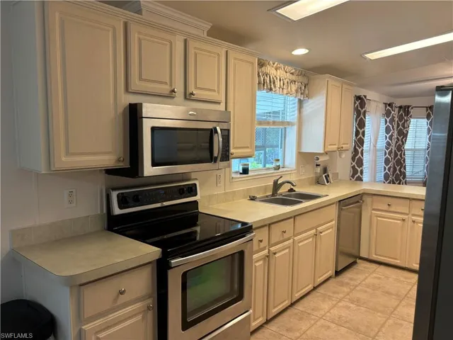 Kitchen with appliances with stainless steel finishes, sink, and light tile flooring