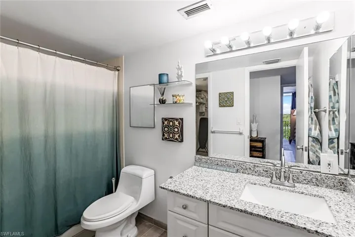 Bathroom with vanity with granite countertop and ample cabinet space.