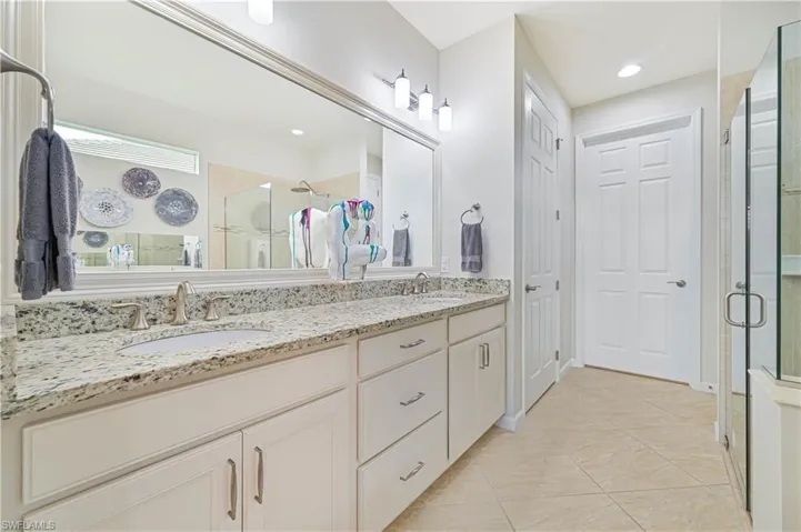 Bathroom with a shower stall, double vanity, tile patterned flooring, and recessed lighting