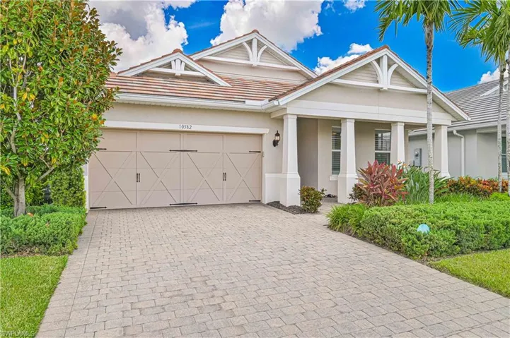 View of front of property with stucco siding, decorative driveway, a garage, a tiled roof, and covered porch