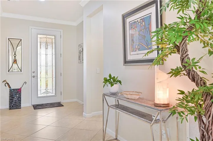 Entryway with ornamental molding, light tile patterned floors, and healthy amount of natural light