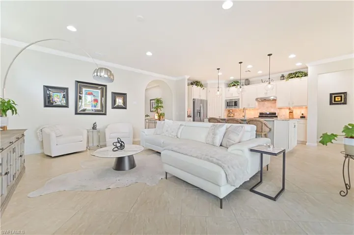 Living area with arched walkways, crown molding, recessed lighting, and light tile patterned flooring