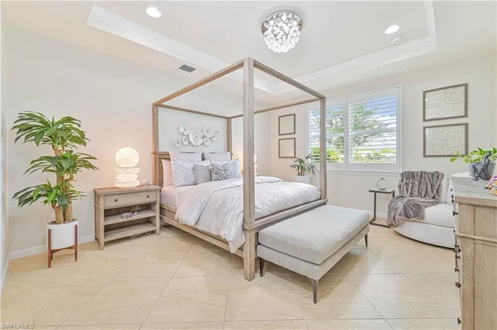 Bedroom with a tray ceiling, crown molding, recessed lighting, and light tile patterned flooring