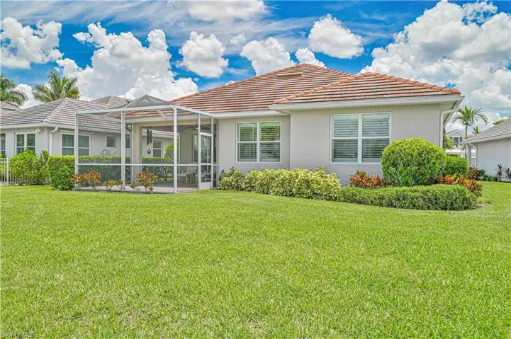 Back of house featuring stucco siding, a tiled roof, and a lawn