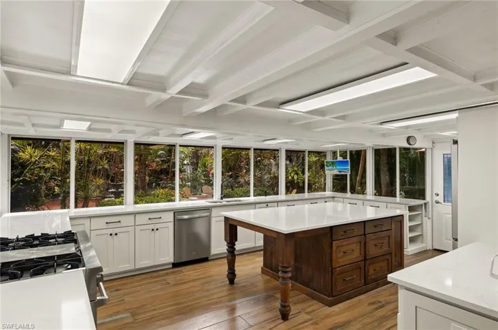 Kitchen featuring stainless steel appliances, light stone counters, light hardwood / wood-style flooring, dark brown cabinetry, and a center island
