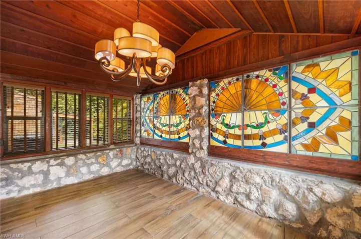 Spare room featuring wooden ceiling, hardwood / wood-style floors, lofted ceiling, and a notable chandelier