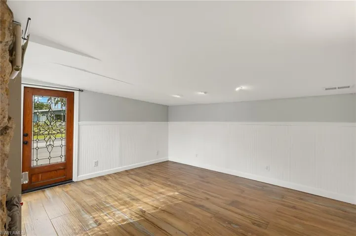 Unfurnished room featuring hardwood / wood-style flooring and lofted ceiling