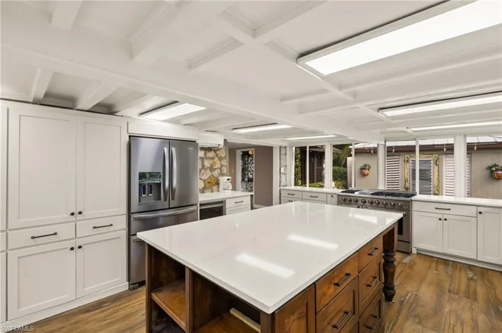 Kitchen featuring a center island, kitchen peninsula, dark wood-type flooring, appliances with stainless steel finishes, and white cabinets