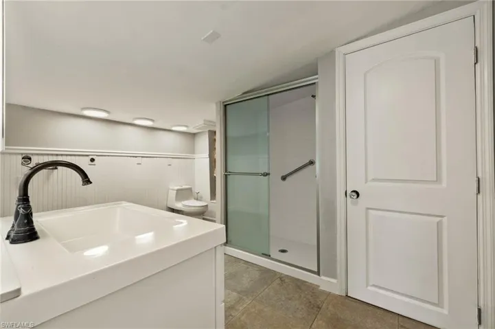 Bathroom with sink, toilet, and a shower with door