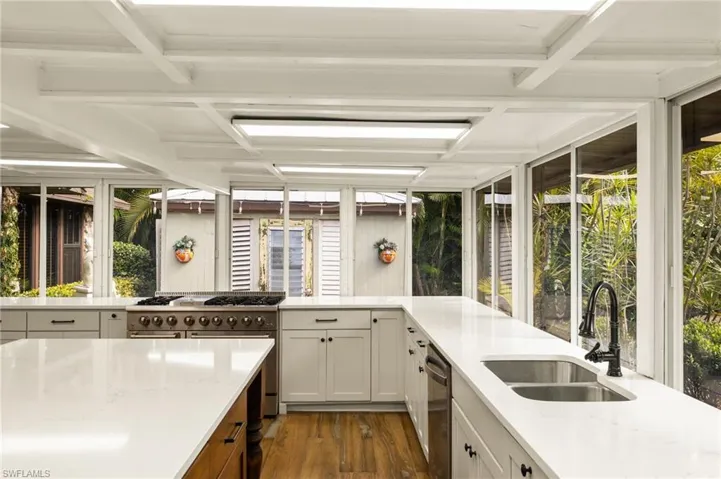 Kitchen with light stone countertops, white cabinets, dark wood-type flooring, stainless steel appliances, and sink