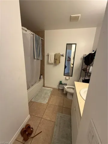 Full bathroom featuring tile patterned flooring, vanity, toilet, and shower / bath combo with shower curtain