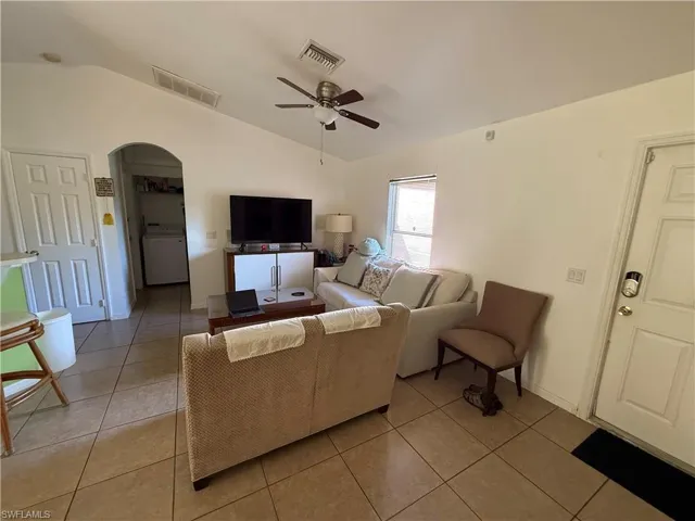 Tiled living room with ceiling fan, lofted ceiling, and washer / dryer