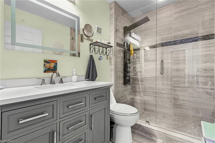 Guest bathroom with vanity, a stall shower, and a textured wall