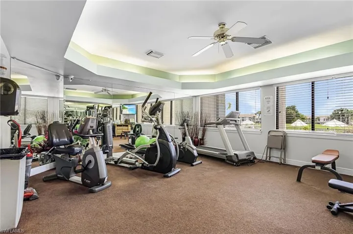 Workout area with ceiling fan and a raised ceiling
