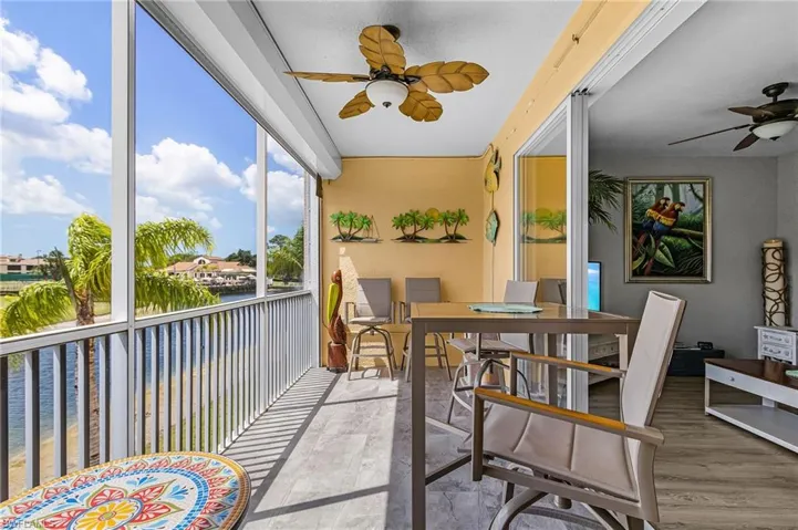 Screened in lanai featuring ceiling fan, outdoor dining space and a water, golf and clubhouse view