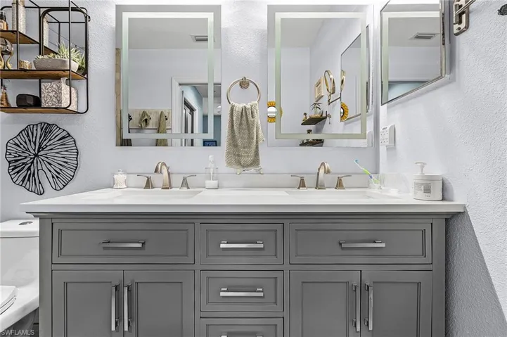 Primary bathroom featuring a textured wall and double vanity